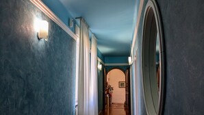 A hallway with blue walls, white curtains, and a wooden floor.