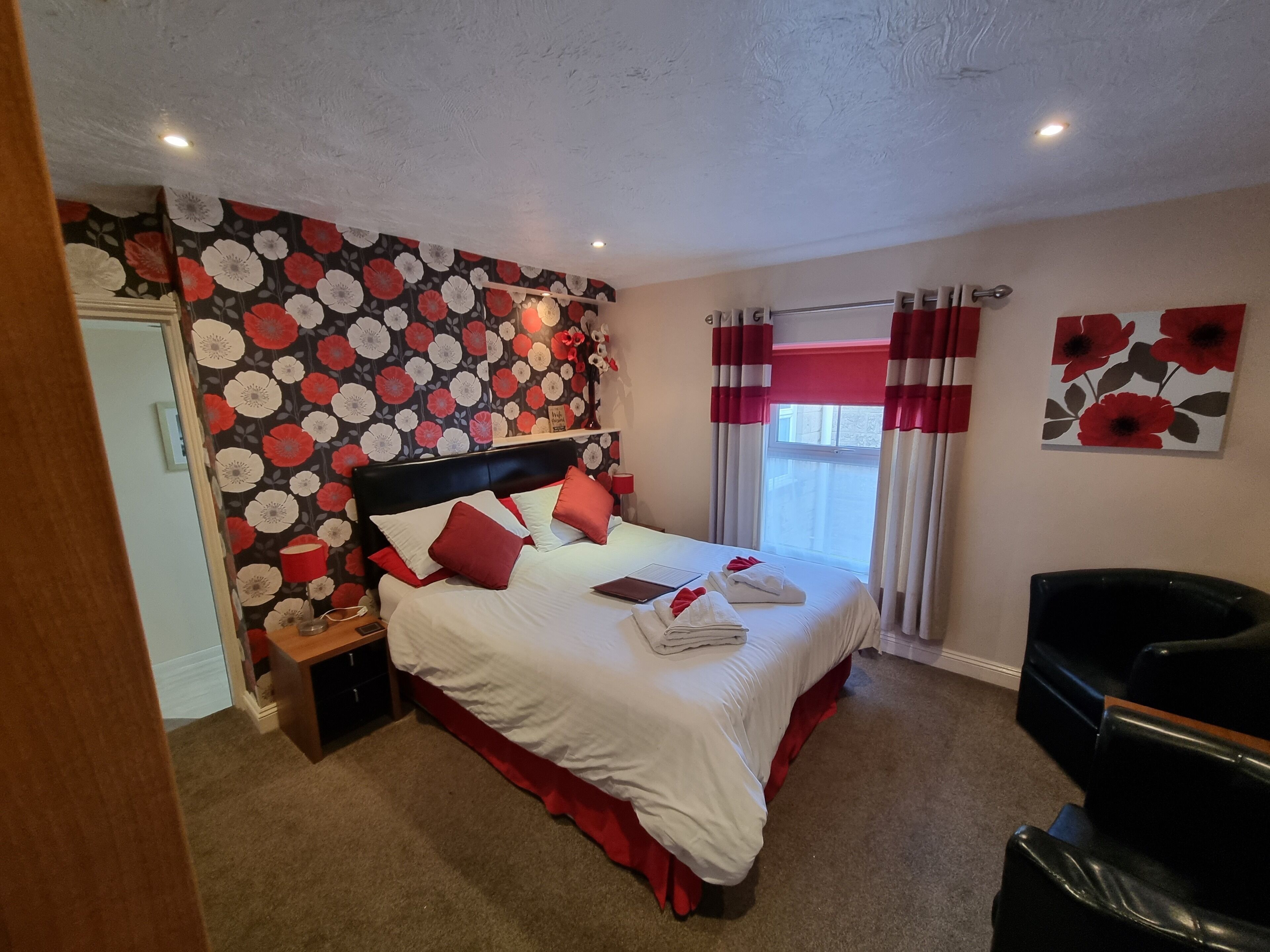 Une chambre d’hôtel avec un lit, une table de chevet, une chaise et une fenêtre avec des rideaux.