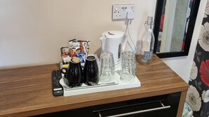 A wooden desk with a remote control, a white kettle, and several glass tumblers. - The Fawley (Shanklin)