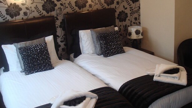 A double bed with two pillows, a bedside lamp, and a folded towel on the bed. - The Fawley (Shanklin)