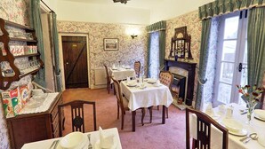 Un comedor con chimenea, una estantería y una mesa de comedor preparada para cuatro personas.