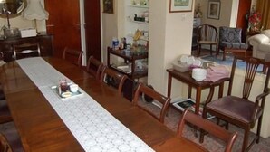 Zona pranzo con un lungo tavolo in legno, sedie e un runner da tavolo decorato.