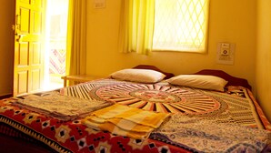 A room with a bed, a window with yellow curtains, and a door. - Yellow House (Vagator)
