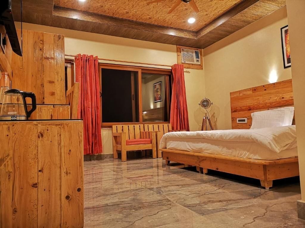 Une chambre à coucher avec un lit en bois, une commode en bois, une chaise et une fenêtre avec des rideaux.