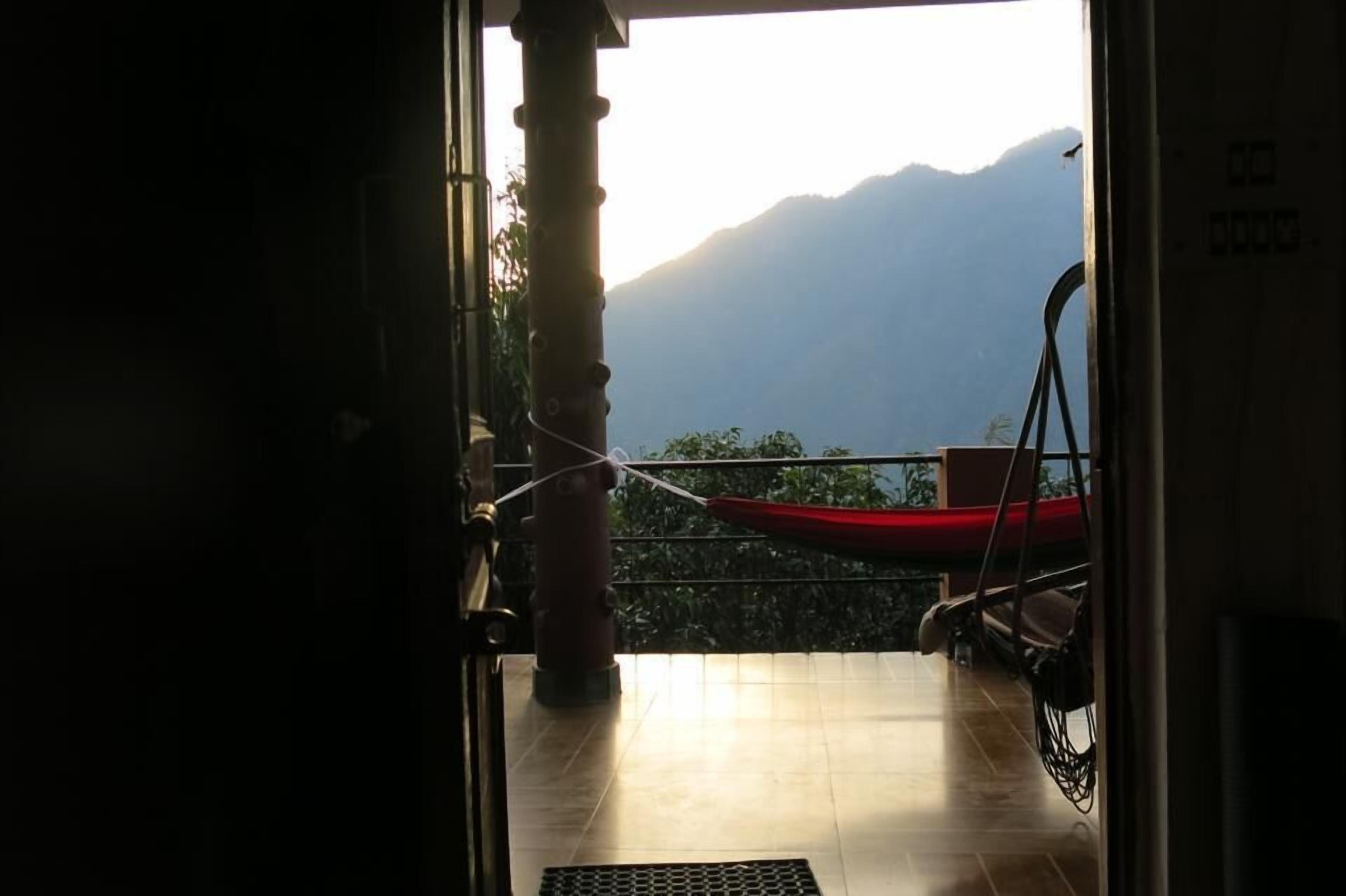 Un balcón con vistas a montañas, un barco rojo y una barandilla de metal.