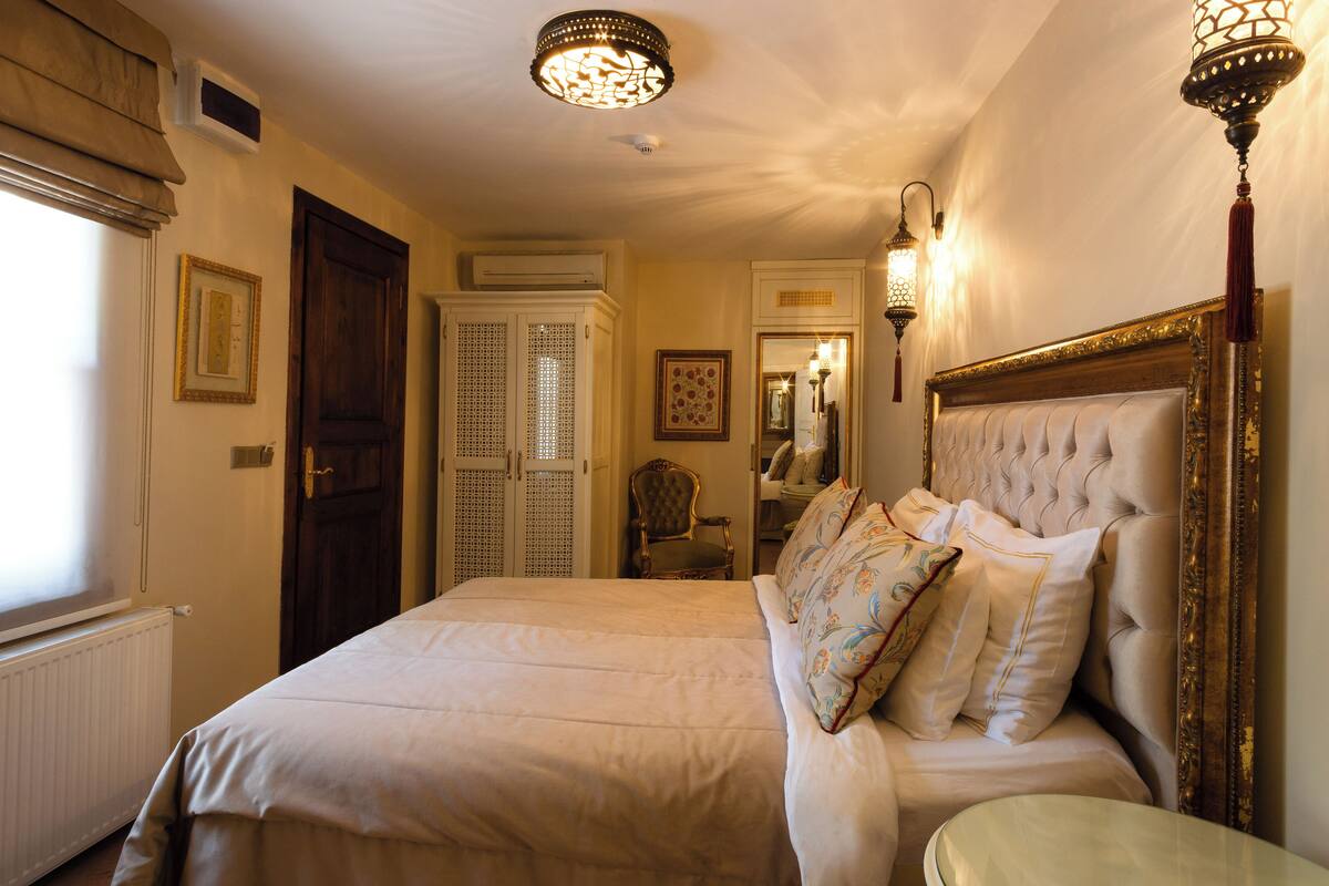 Quarto com cama grande, guarda-roupa de madeira, cadeira e espelho.