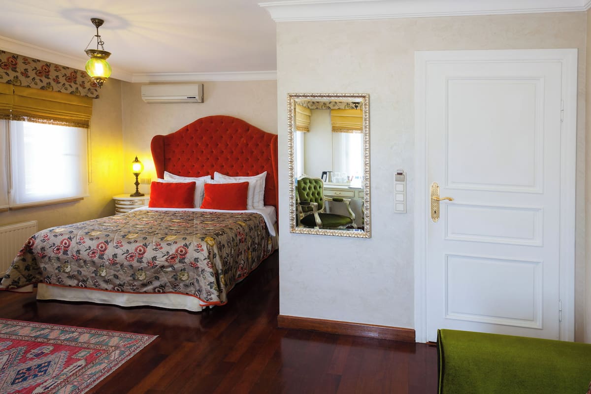 Quarto com uma cama grande, cômoda, espelho e porta.
