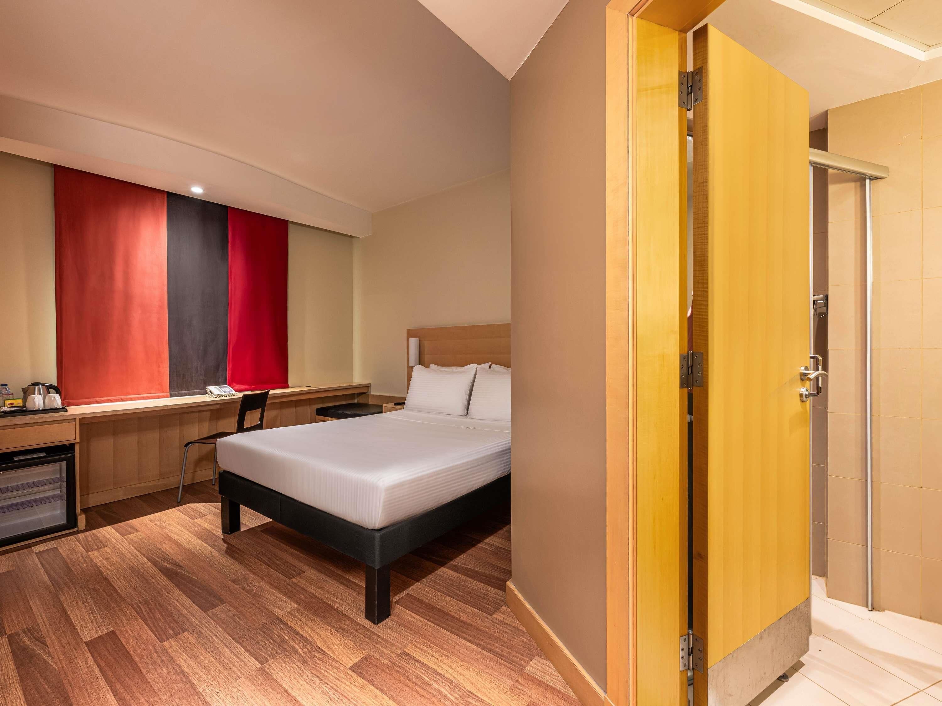 Une chambre d’hôtel avec un lit, un bureau, une chaise et une porte.