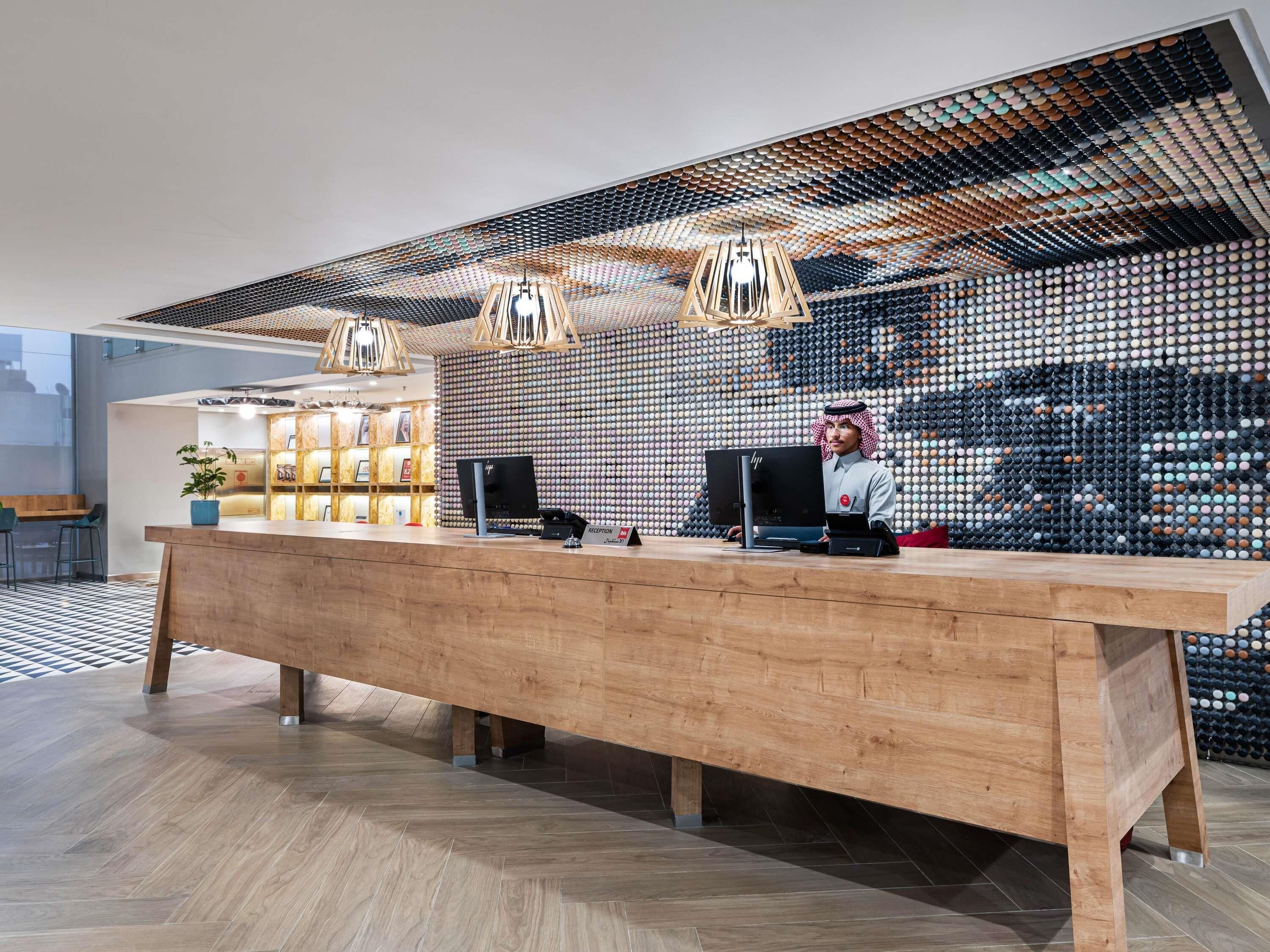 A reception desk with a modern design, a wooden floor, and a wall with a unique pattern.