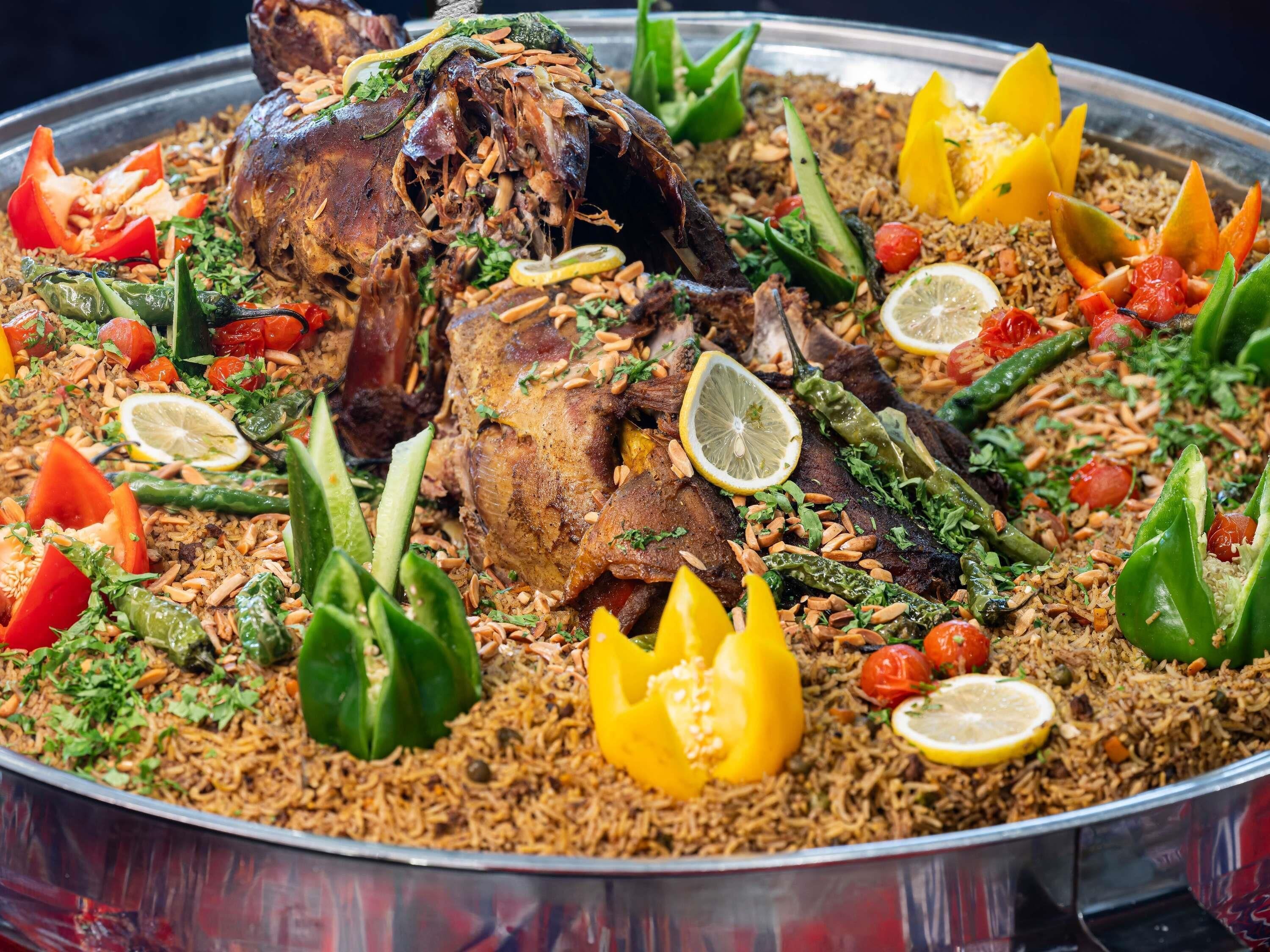 A large platter of biryani with meat, vegetables, and garnishes.