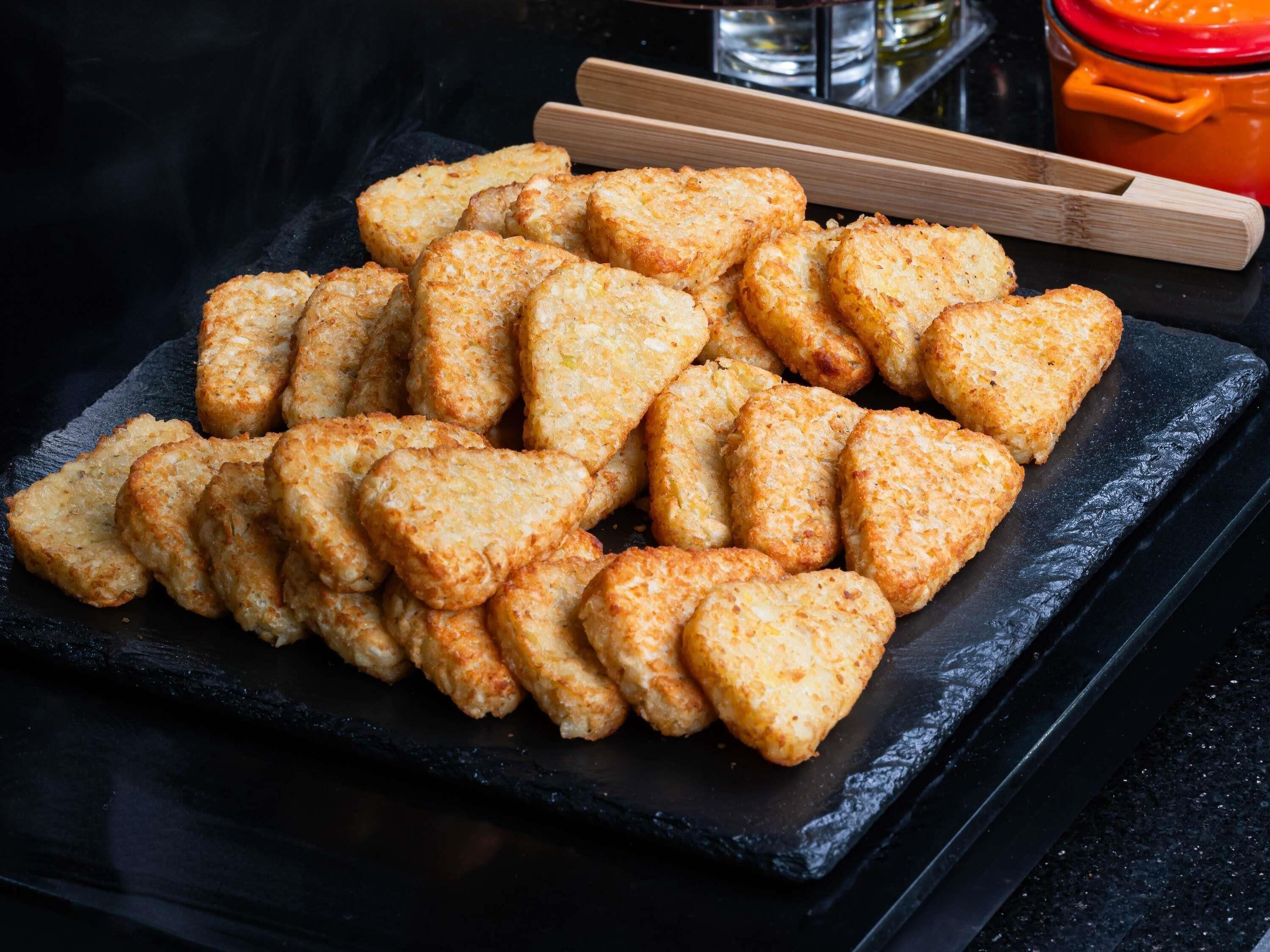 Une assiette d’ardoise noire sur laquelle sont disposés des biscuits triangulaires, dorés et croustillants.