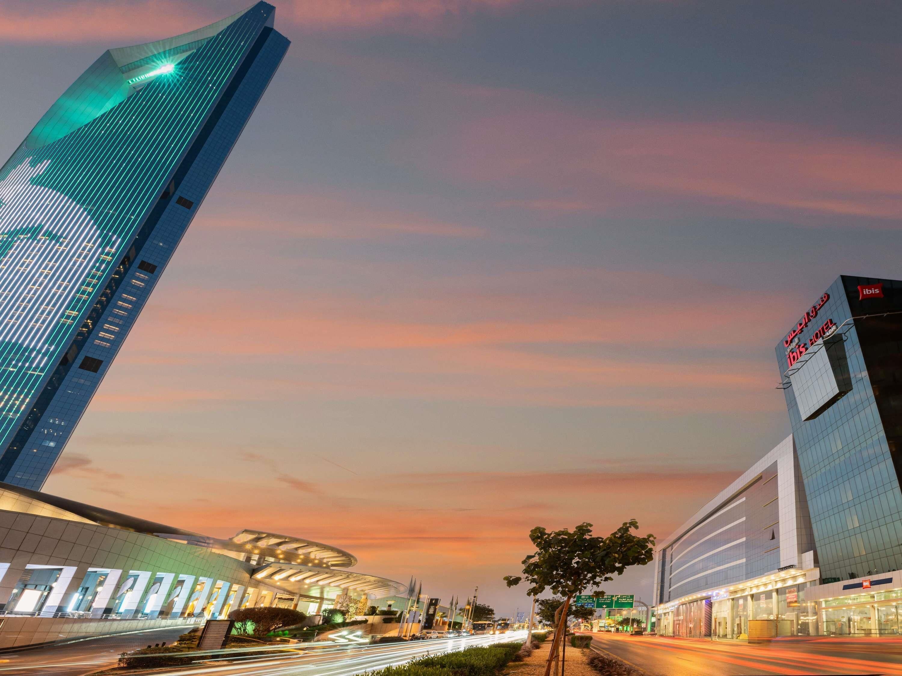 A modern hotel with a curved glass facade and a prominent 'ibis' sign.