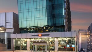 A modern hotel with a glass facade, a prominent sign, and a well-lit entrance.