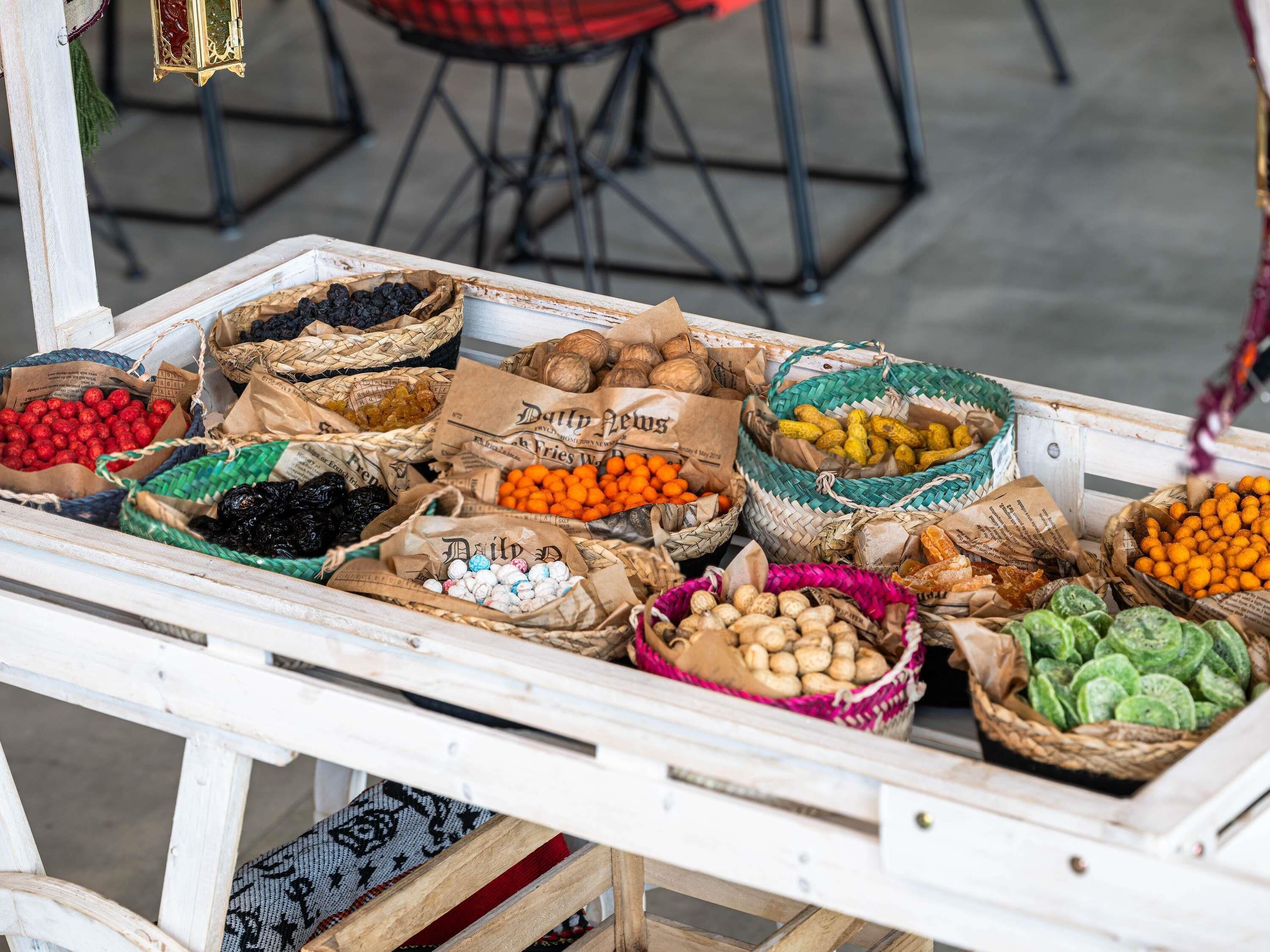Uma banca de mercado com diversos cestos de frutas e frutos secos.