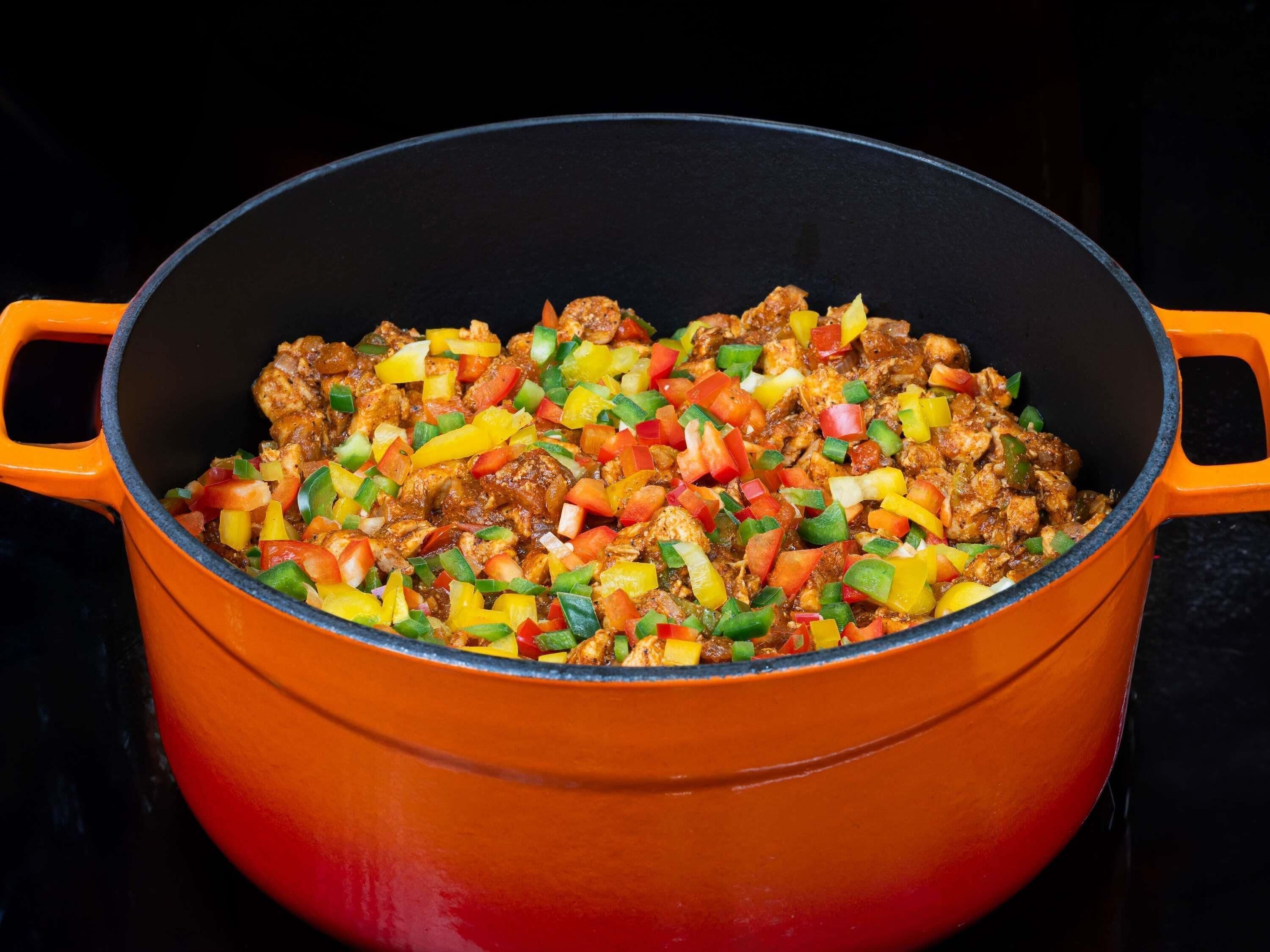 Een grote oranje pot gevuld met een kleurrijke roerbakschotel.