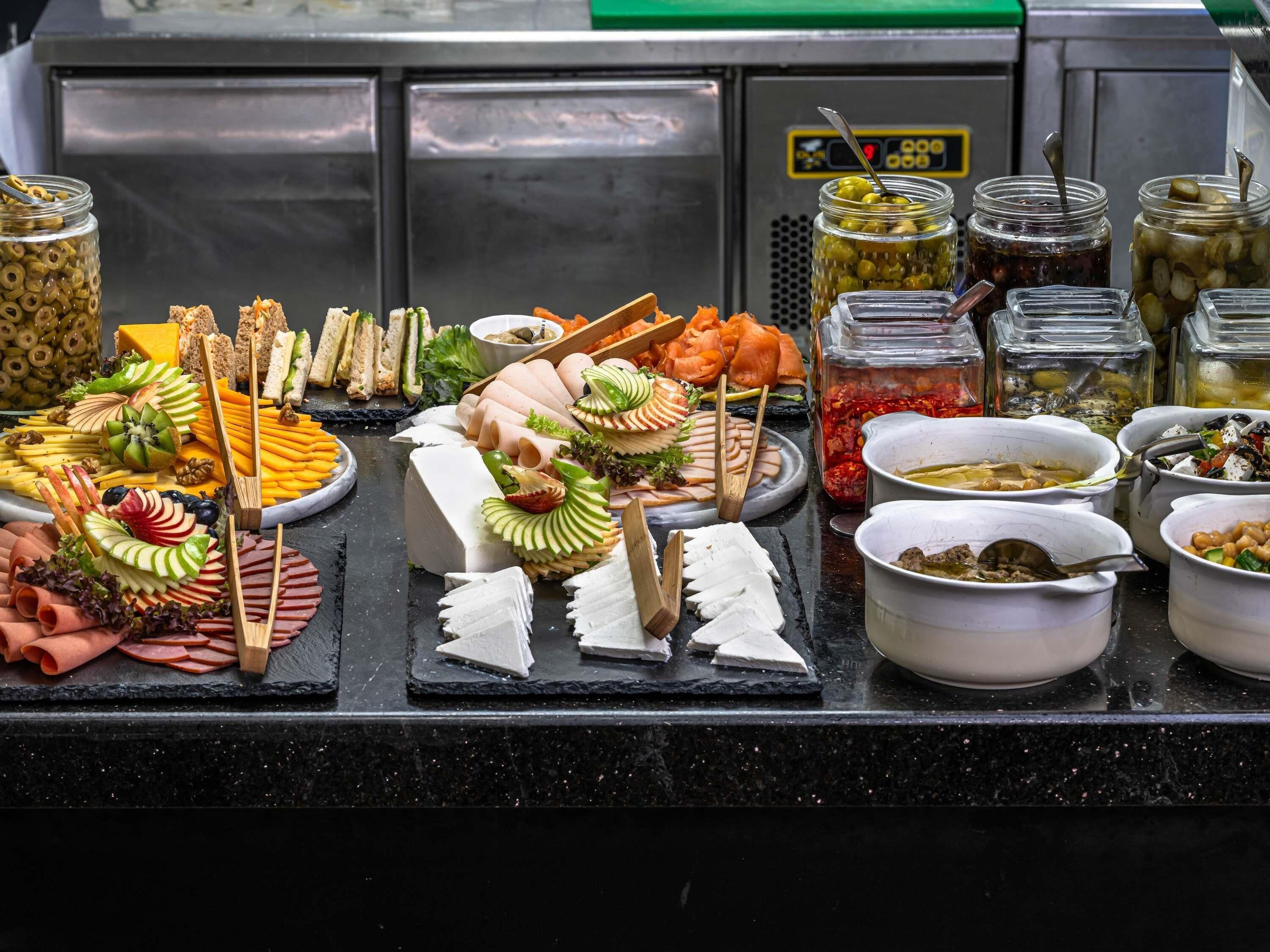 A buffet with various food items including meats, cheeses, and fruits.
