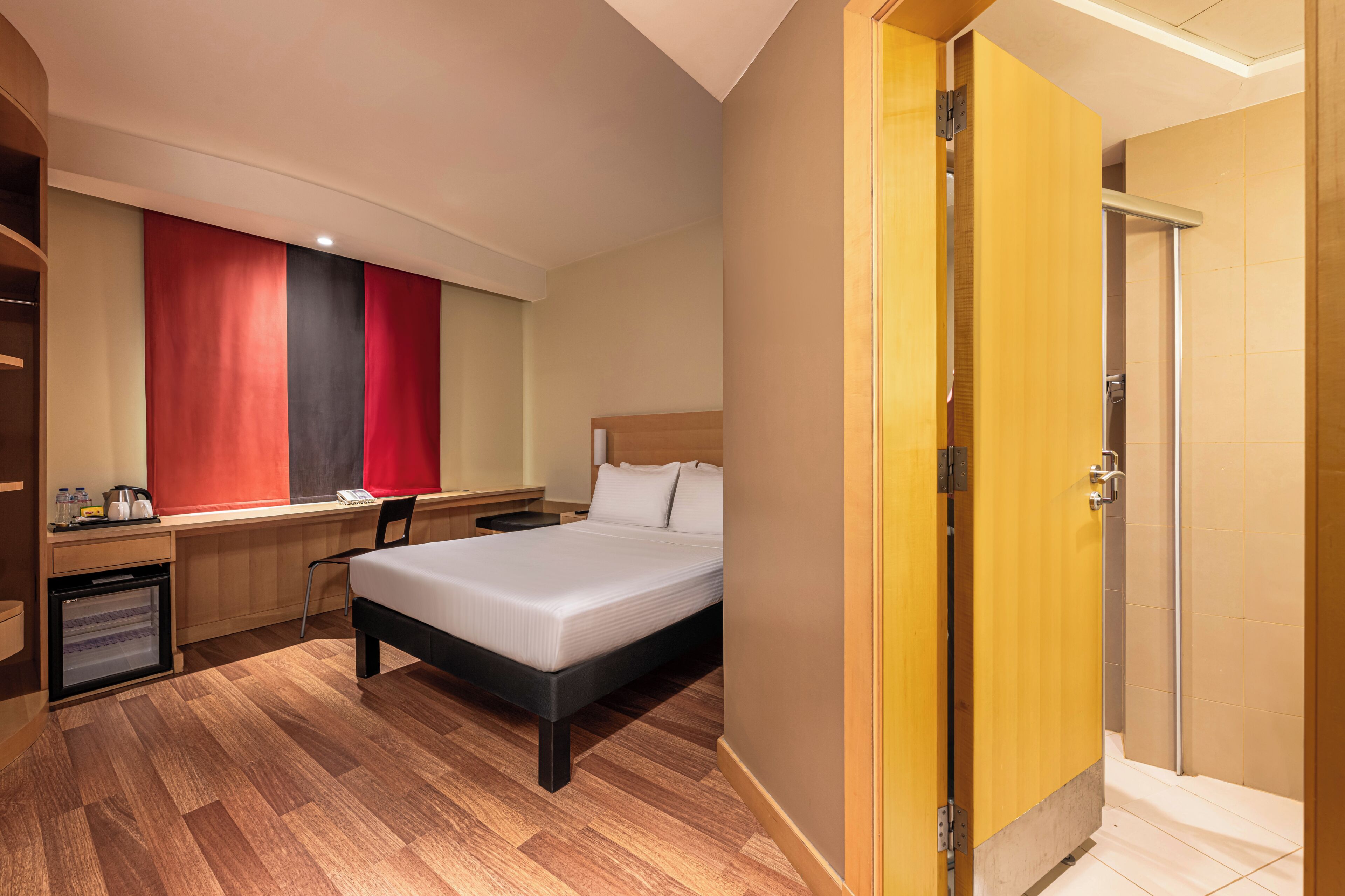 A hotel room with a bed, desk, chair, and a wardrobe.
