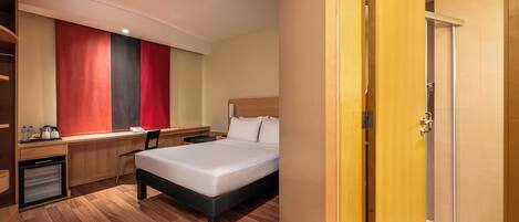 A hotel room with a bed, desk, chair, and a wardrobe.