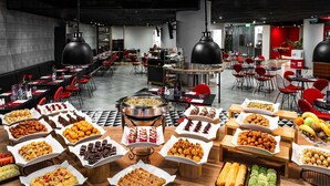A buffet with various food items, a modern interior with red chairs, and a checkered floor. - Ibis Riyadh Hotel Al Muhammadiyah United Company Branch (Riyadh)