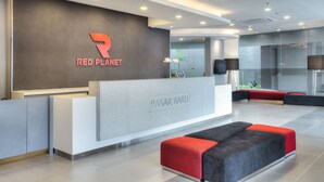 Un espace d’accueil moderne avec un comptoir de réception gris, un logo rouge et une cloison en verre.