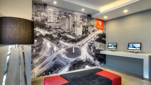 Un hall d’entrée moderne agrémenté d’une fresque représentant un paysage urbain, d’un comptoir d’accueil et de plusieurs espaces de détente.