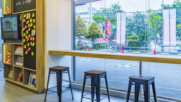 Un intérieur moderne avec un bar, des sièges et une grande fenêtre donnant sur la rue.