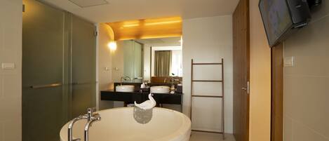 Une salle de bain moderne avec une baignoire sur pieds, un meuble-lavabo avec deux vasques, un miroir et un téléviseur fixé au mur.