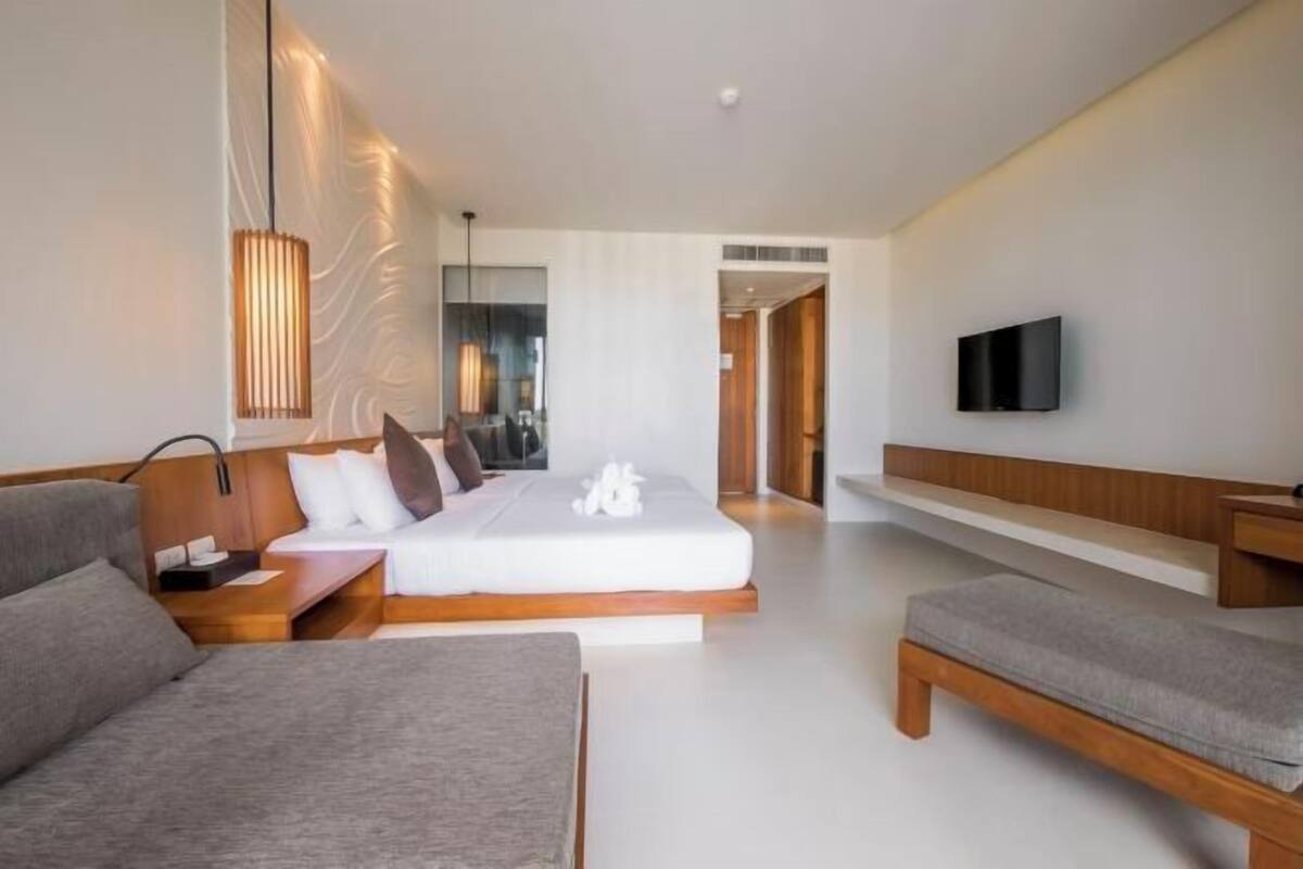 Une chambre d’hôtel moderne équipée d’un lit, d’un canapé, d’une télévision et d’une table de chevet.
