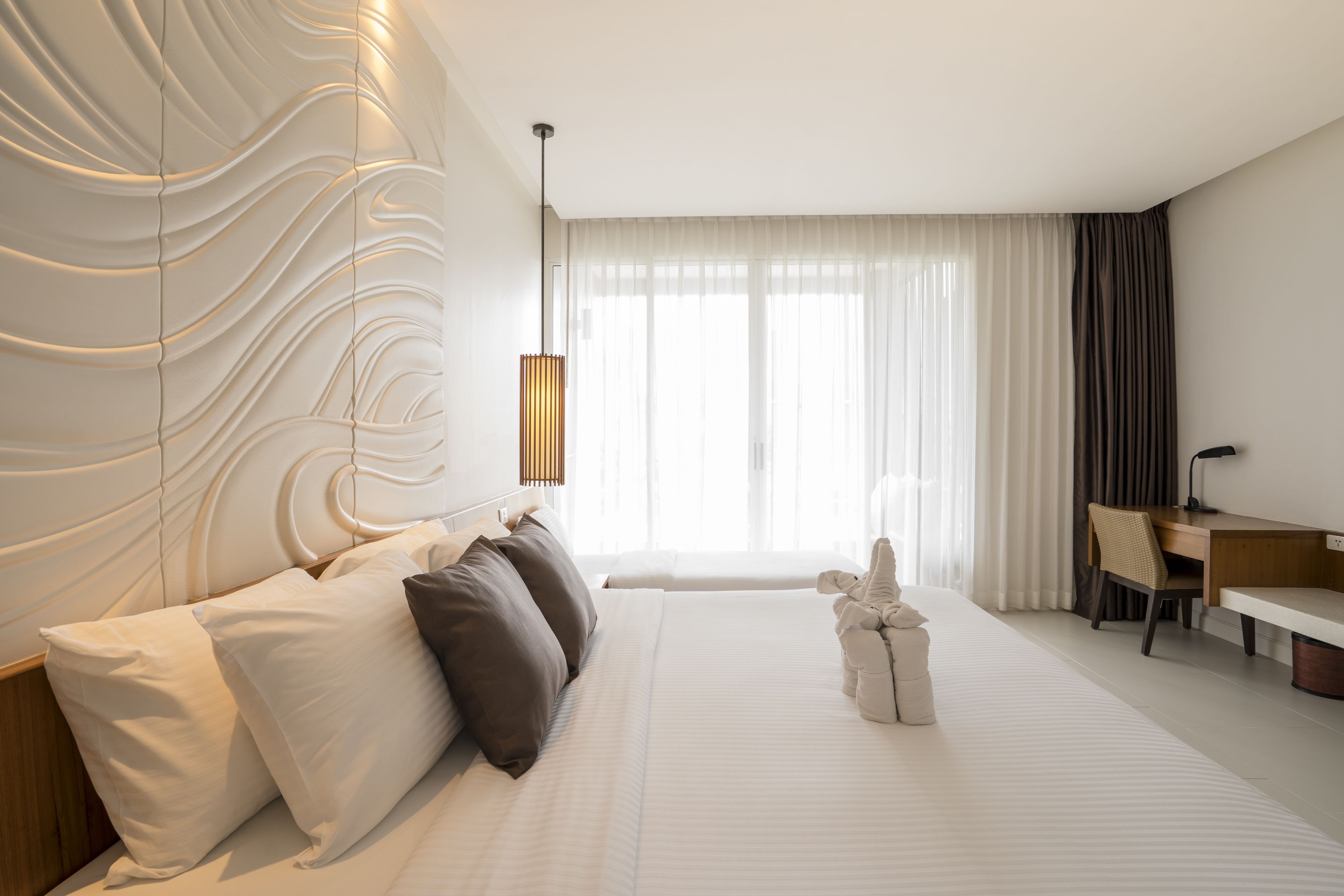 A modern hotel room with a large bed, a desk, and a view of the city.