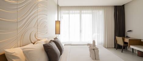 A modern hotel room with a large bed, a desk, and a view of the city.