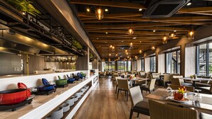 Een modern restaurantinterieur met houten vloeren, lange gedeelde tafels en hangende pendantlampen.