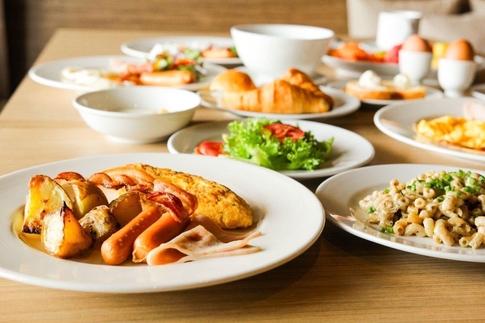 A breakfast buffet with various dishes including eggs, pastries, and salads.