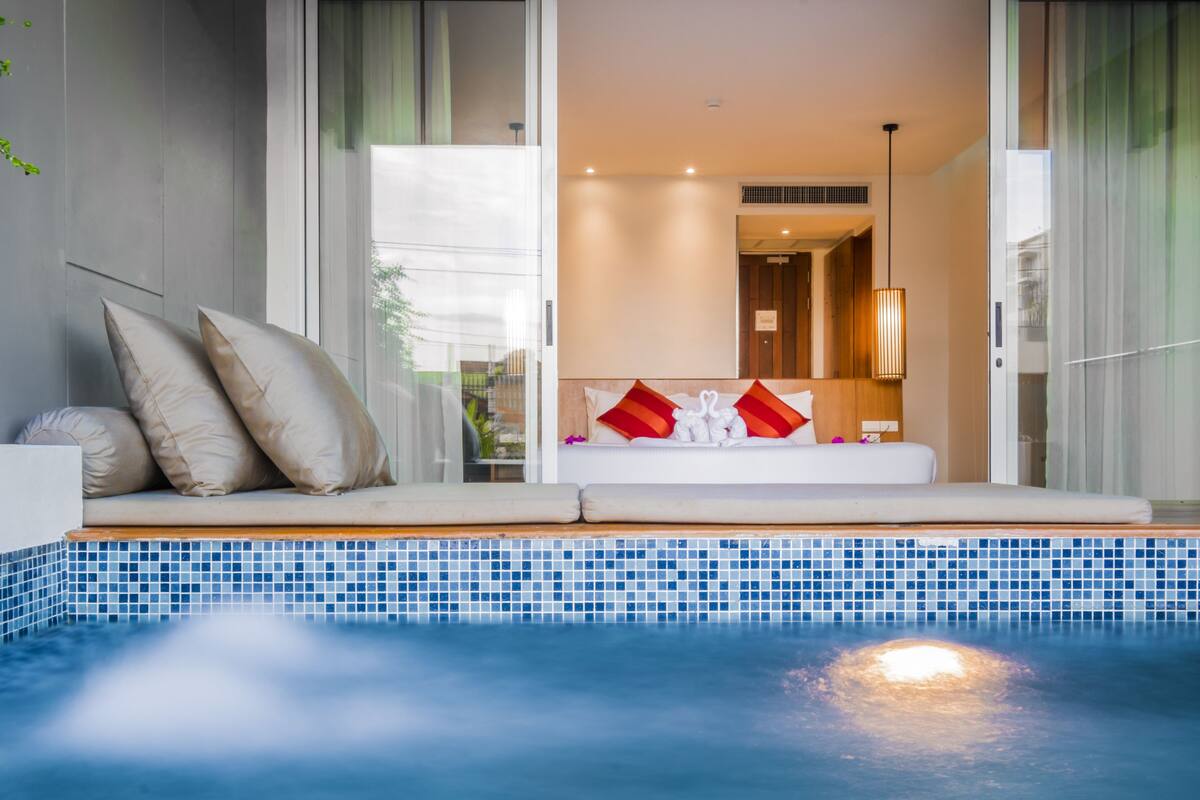 Une chambre d’hôtel moderne avec un balcon privé donnant sur une piscine.