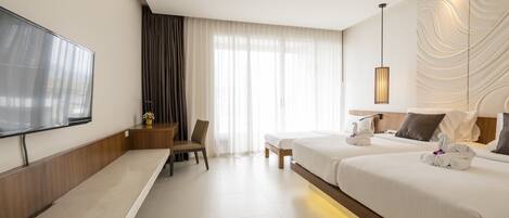 Une chambre d’hôtel moderne équipée d’une télévision à écran plat, d’un bureau, de deux lits et d’une grande fenêtre avec des rideaux.