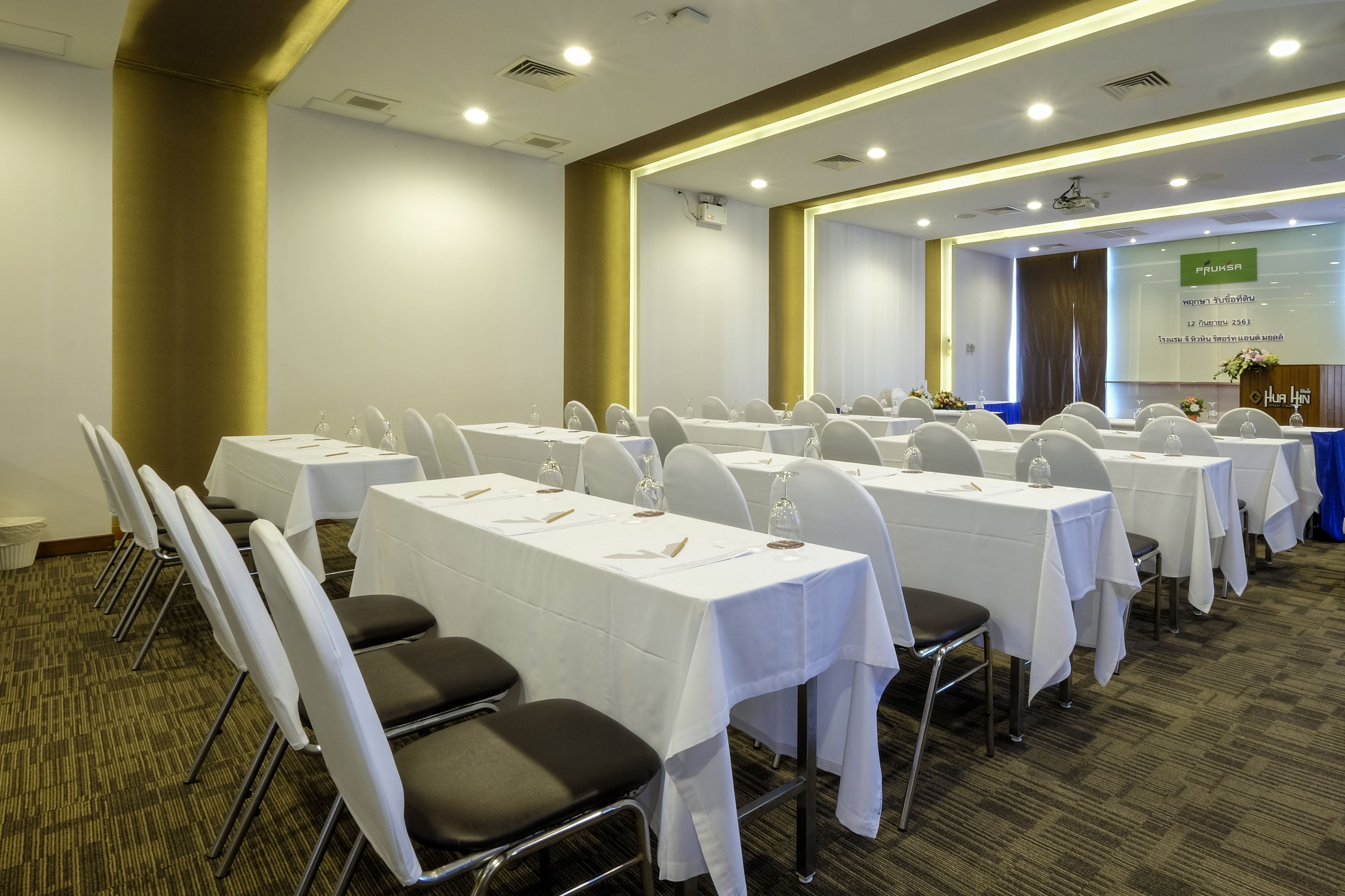 A conference room with multiple tables and chairs, equipped with nameplates and water glasses.