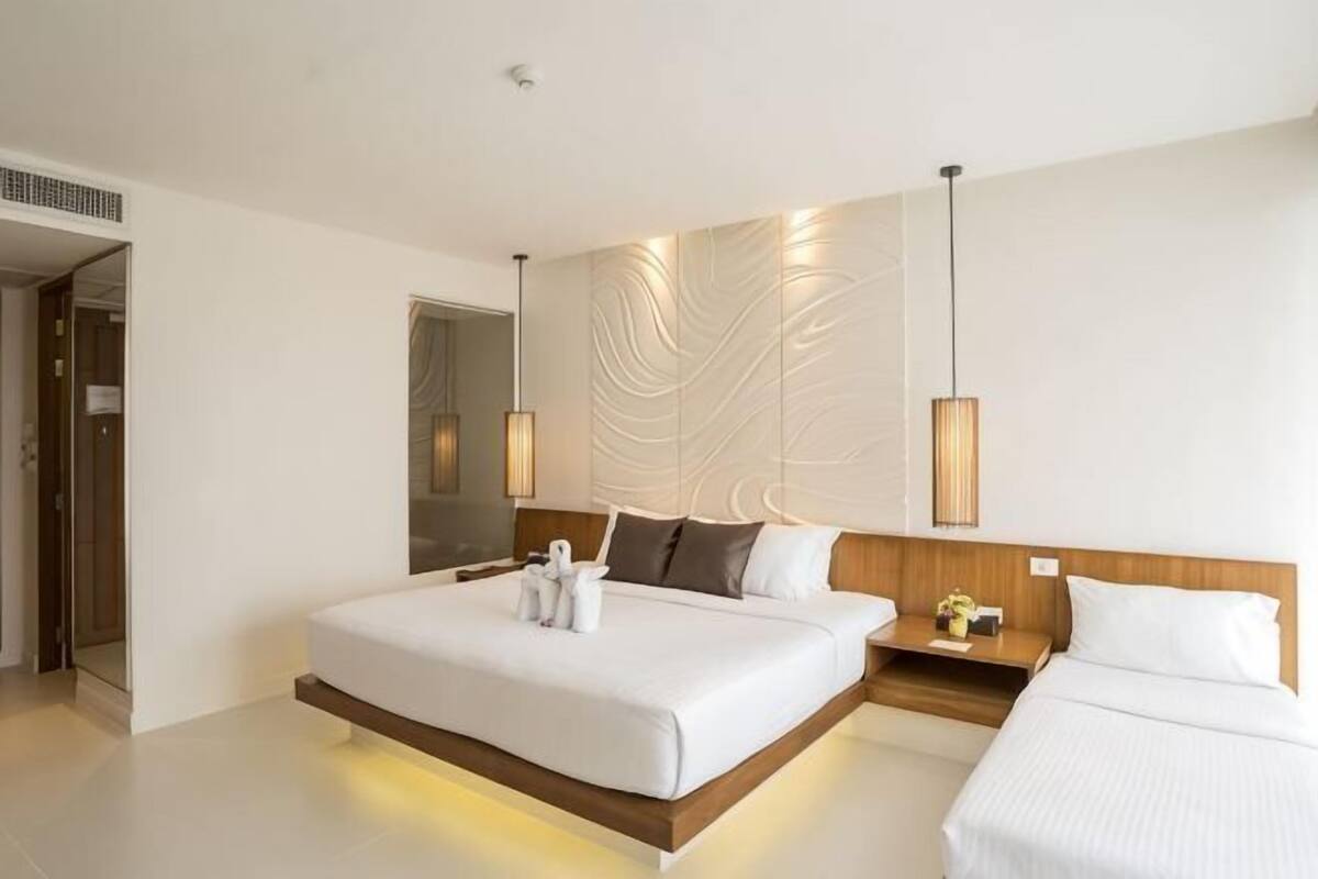Une chambre d’hôtel moderne avec un grand lit, des tables de chevet et un luminaire fixé au mur.