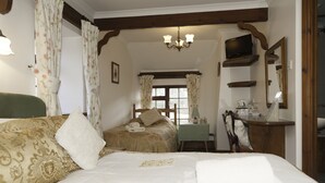 A hotel room with two beds, a television, a mirror, and a small table with a lamp. - Burton Farmhouse (Kingsbridge)