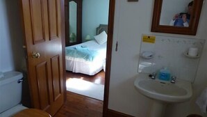 A bathroom with a wooden door, a toilet, and a sink. - Burton Farmhouse (Kingsbridge)
