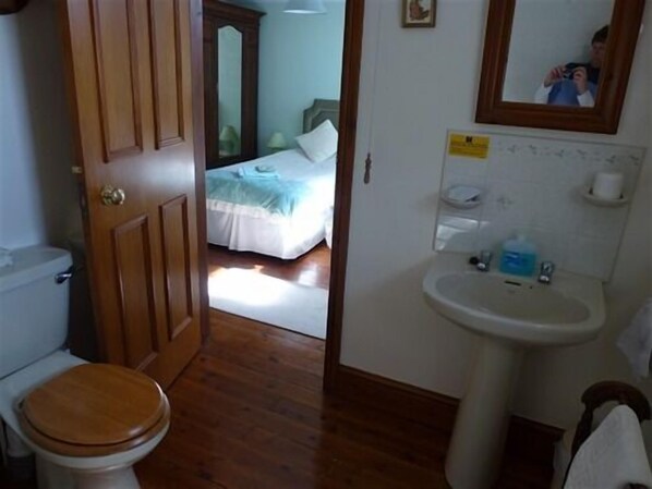 Une salle de bain avec une porte en bois, des toilettes et un lavabo.