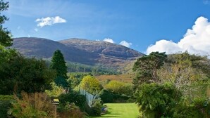 A lush green landscape with a clear sky, a mountain in the background, and a well-maintained lawn in the foreground. - Cherryhill Lodge (Newcastle)
