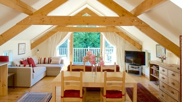 An attic room with a dining table, chairs, a sofa, and a TV. - Cherryhill Lodge (Newcastle)