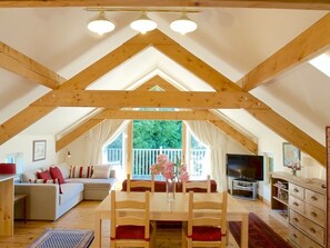 An attic room with a dining table, chairs, a sofa, and a TV. - Cherryhill Lodge (Newcastle)