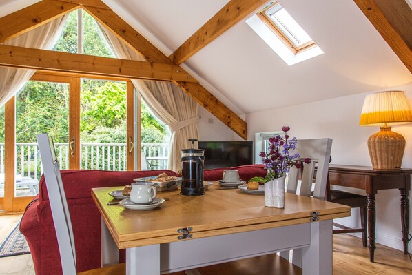 A cozy dining area with a wooden table, red upholstered chairs, and a view of the outdoors through large windows. - Cherryhill Lodge (Newcastle)