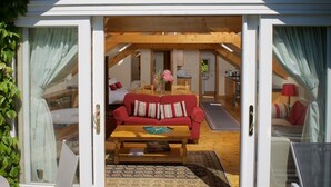 A cozy interior with a red sofa, wooden coffee table, and a dining area. - Cherryhill Lodge (Newcastle)