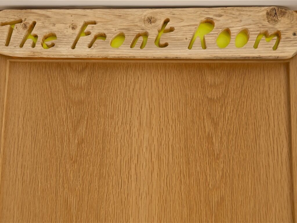 A wooden sign with the text "The Front Room" carved into it.