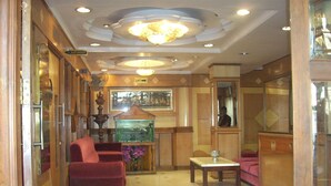 Een hotellobby met een receptiebalie, een aquarium en zitgedeeltes.