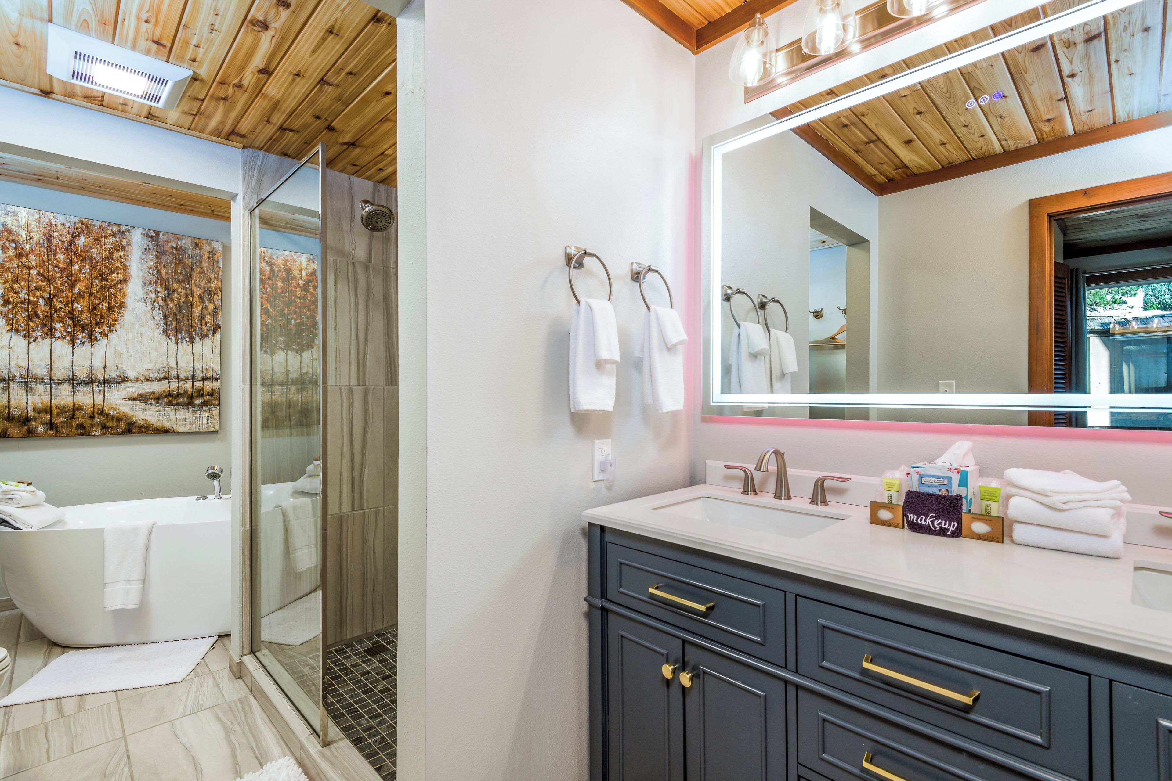Un baño moderno con una bañera independiente, cabina de ducha con paredes de cristal y un tocador con un espejo grande.
