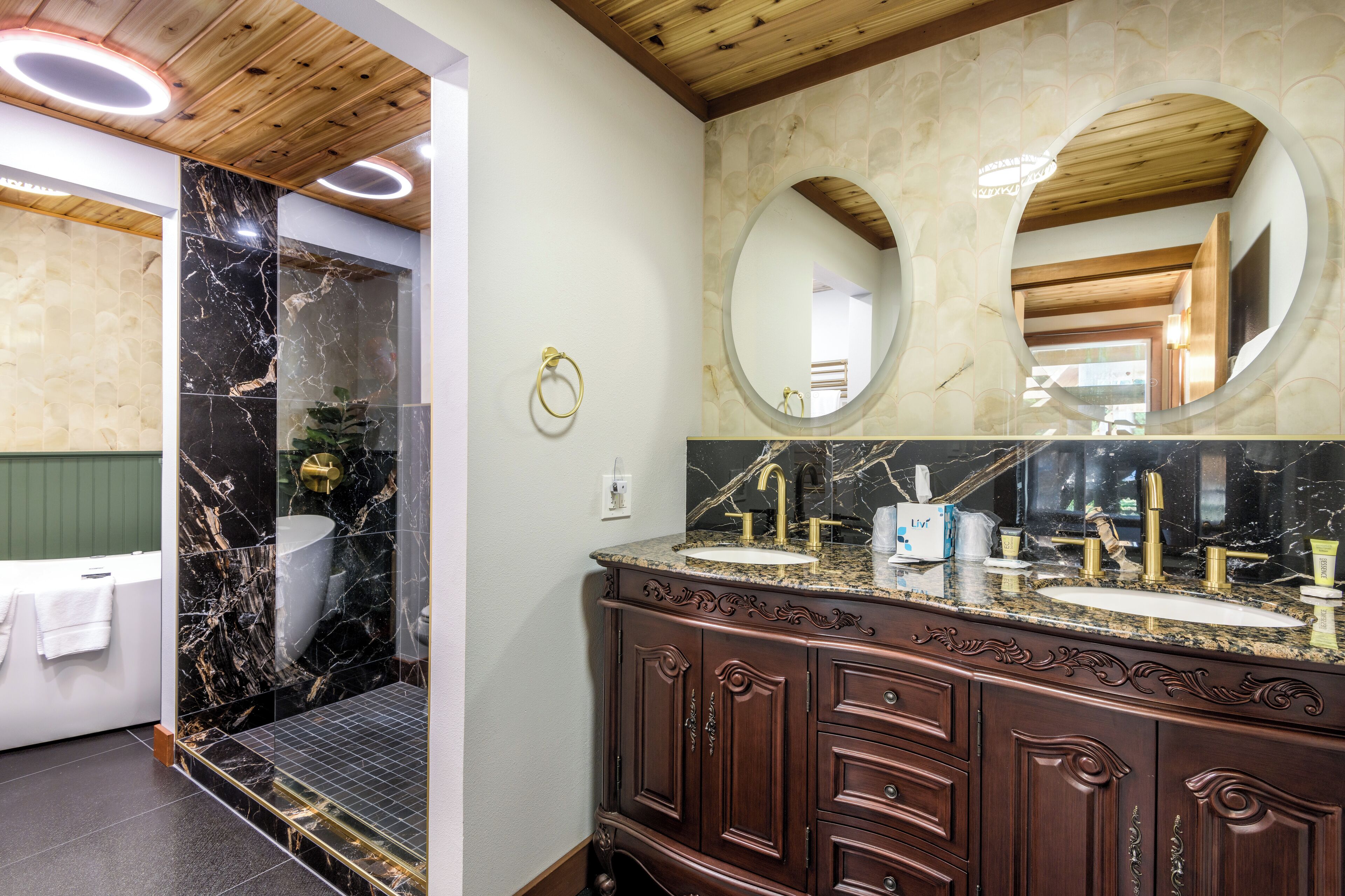 Un baño con tocador de mármol, dos lavamanos, un espejo grande y una zona de ducha.