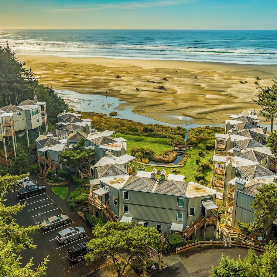 A coastal residential area with houses, a beach, and a parking lot.
