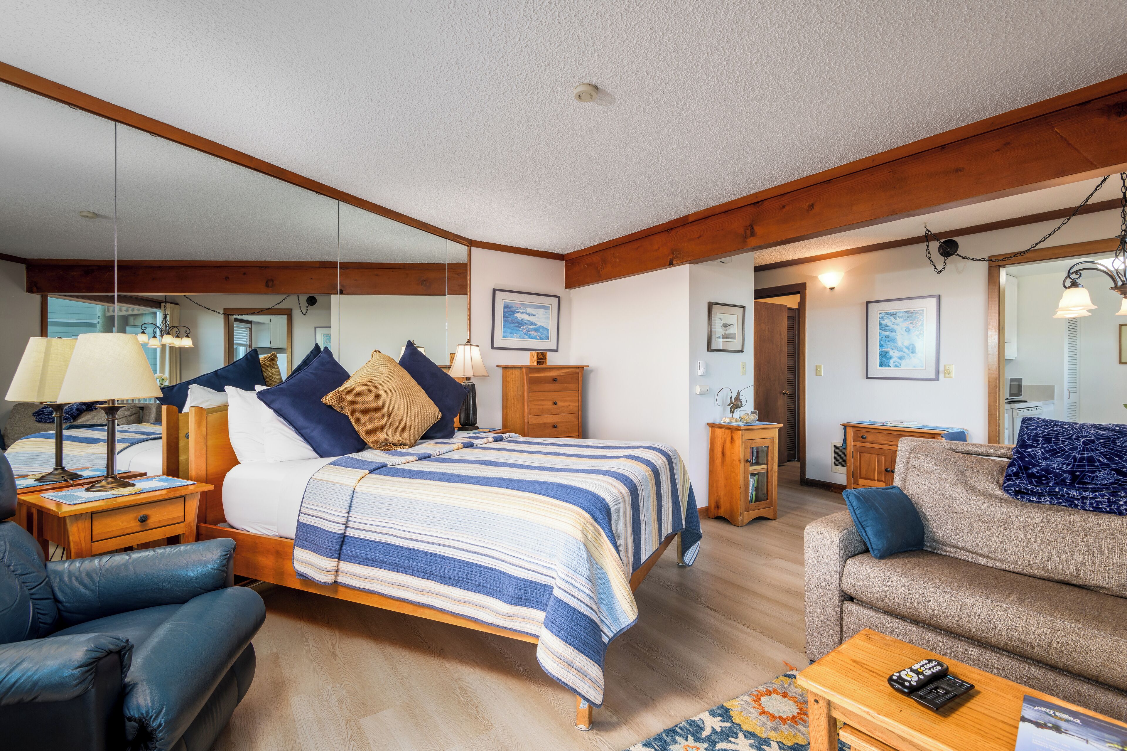 Una habitación luminosa con cama, sofá, una mesa de centro de madera y una lámpara.